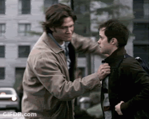 Two Men Are Standing Next To Each Other And One Is Holding The Other 'S Collar GIF