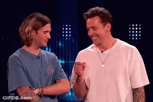 Two Men Are Standing Next To Each Other And One Is Pointing At The Other GIF