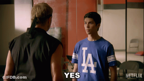 Two Men Are Standing Next To Each Other And One Of Them Is Wearing A La Shirt GIF