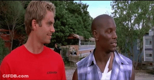 Two Men Are Standing Next To Each Other And One Of Them Is Wearing A Red Shirt That Says Greddy On It GIF