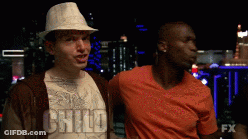 Two Men Are Standing Next To Each Other And One Of Them Is Wearing An Orange Shirt With The Word Fx On It GIF