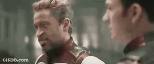 Two Men Are Standing Next To Each Other And Talking To Each Other In A Dark Room . GIF