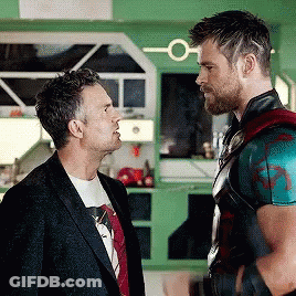 Two Men Are Standing Next To Each Other And Talking To Each Other In A Kitchen . GIF