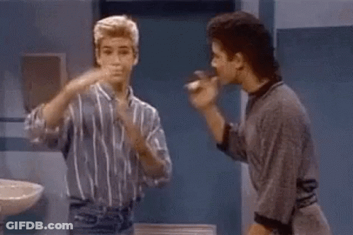 Two Men Are Standing Next To Each Other In A Bathroom . GIF