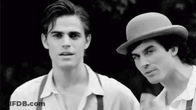 Two Men Are Standing Next To Each Other In A Black And White Photo . One Of The Men Is Wearing A Bowler Hat . GIF
