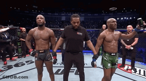 Two Men Are Standing Next To Each Other In A Boxing Ring And One Of Them Is Wearing A Ufc Shorts GIF