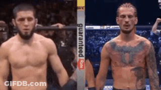 Two Men Are Standing Next To Each Other In A Boxing Ring Holding Hands . GIF