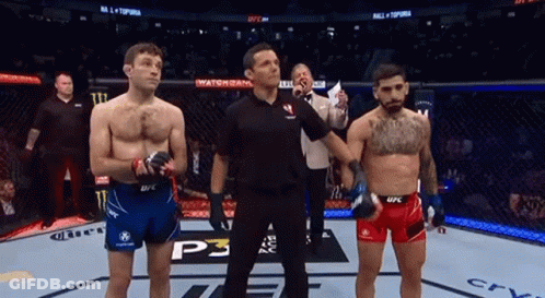 Two Men Are Standing Next To Each Other In A Boxing Ring With A Referee . GIF