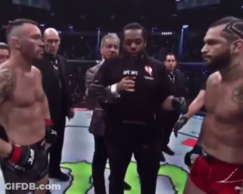 Two Men Are Standing Next To Each Other In A Boxing Ring With A Referee Holding A Microphone . GIF