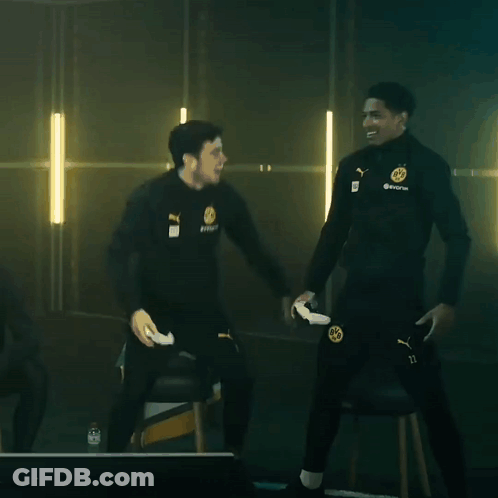 Two Men Are Standing Next To Each Other In A Dark Room And One Of Them Is Holding A Remote Control GIF