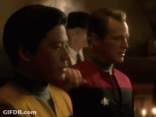 Two Men Are Standing Next To Each Other In A Dark Room . One Of The Men Has A Star On His Uniform . GIF