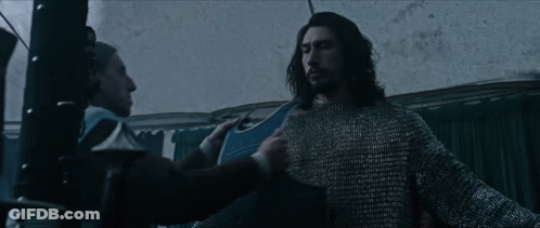Two Men Are Standing Next To Each Other In A Dark Room . One Of The Men Is Wearing A Chain Mail Sweater . GIF