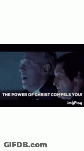 Two Men Are Standing Next To Each Other In A Dark Room With The Words `` The Power Of Christ Compels You '' . GIF