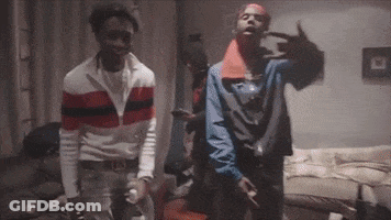 Two Men Are Standing Next To Each Other In A Living Room And Making A Peace Sign . GIF