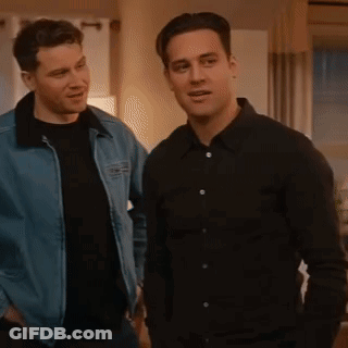 Two Men Are Standing Next To Each Other In A Living Room . One Of The Men Is Wearing A Denim Jacket . GIF