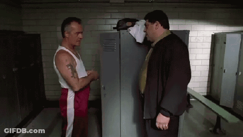 Two Men Are Standing Next To Each Other In A Locker Room Talking . GIF