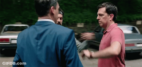 Two Men Are Standing Next To Each Other In A Parking Lot . GIF