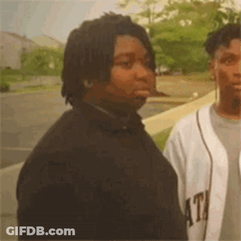 Two Men Are Standing Next To Each Other In A Parking Lot . GIF