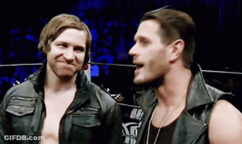 Two Men Are Standing Next To Each Other In A Ring And One Of Them Is Wearing A Leather Vest GIF