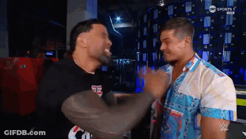 Two Men Are Standing Next To Each Other In A Room And Having A Conversation . GIF
