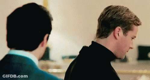 Two Men Are Standing Next To Each Other In A Room And Looking At Each Other . GIF
