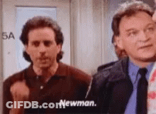 Two Men Are Standing Next To Each Other In A Room And One Of Them Is Named Newman . GIF