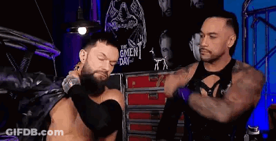 Two Men Are Standing Next To Each Other In A Room . One Of The Men Is Wearing A Leather Jacket . GIF