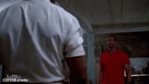 Two Men Are Standing Next To Each Other In A Room . One Of The Men Is Wearing A Red Shirt . GIF