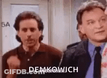 Two Men Are Standing Next To Each Other In A Room . One Of The Men Is Wearing A Tie . GIF