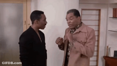 Two Men Are Standing Next To Each Other In A Room Talking To Each Other . GIF