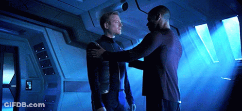 Two Men Are Standing Next To Each Other In A Room With A Blue Light Coming Through The Windows GIF