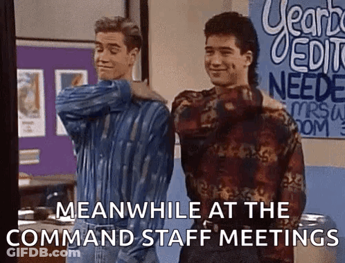 Two Men Are Standing Next To Each Other In A Room With A Sign That Says Meanwhile At The Command Staff Meetings . GIF