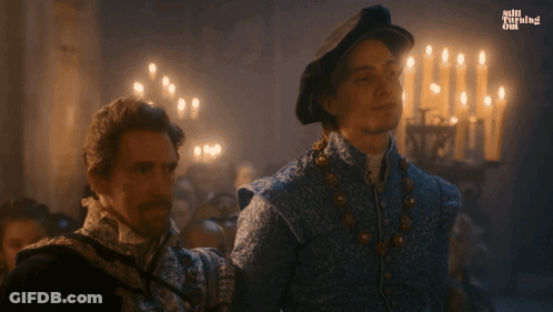 Two Men Are Standing Next To Each Other In A Room With Candles And The Words Still Burning On The Bottom Left GIF