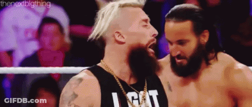Two Men Are Standing Next To Each Other In A Wrestling Ring . One Of The Men Has A Beard . GIF