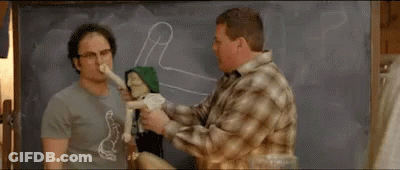 Two Men Are Standing Next To Each Other In Front Of A Blackboard . One Of The Men Is Holding A Stuffed Animal . GIF