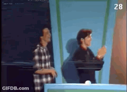 Two Men Are Standing Next To Each Other In Front Of A Blue Wall . GIF