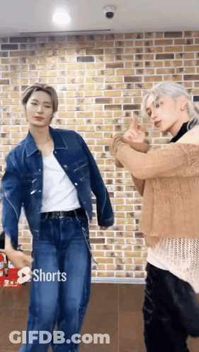 Two Men Are Standing Next To Each Other In Front Of A Brick Wall . GIF