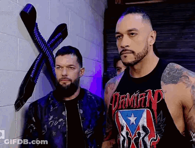 Two Men Are Standing Next To Each Other In Front Of A Brick Wall In A Room . GIF