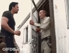 Two Men Are Standing Next To Each Other In Front Of A Building . GIF