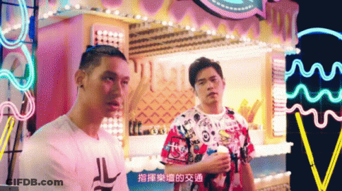 Two Men Are Standing Next To Each Other In Front Of A Carnival Display GIF