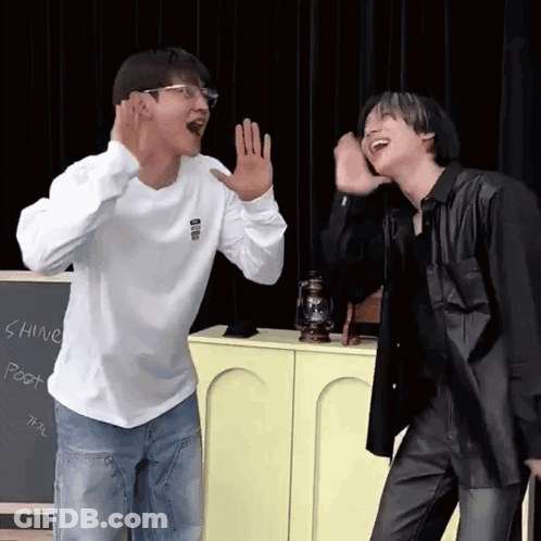 Two Men Are Standing Next To Each Other In Front Of A Chalkboard . GIF