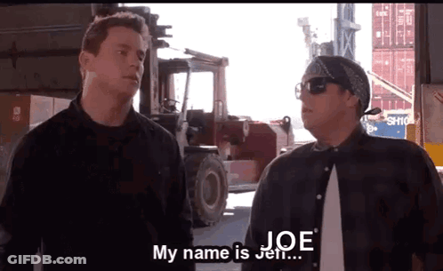 Two Men Are Standing Next To Each Other In Front Of A Forklift And One Of Them Is Saying His Name Is Joe . GIF