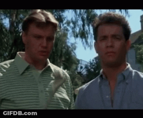 Two Men Are Standing Next To Each Other In Front Of A House And Looking At Each Other . GIF