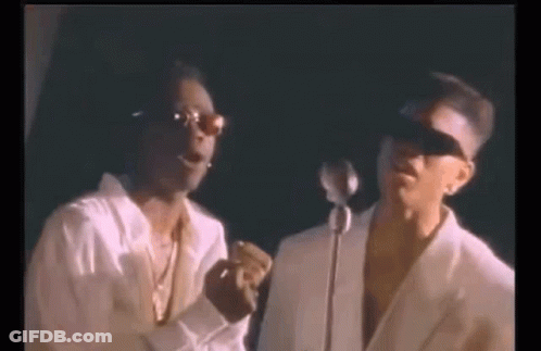 Two Men Are Standing Next To Each Other In Front Of A Microphone And Singing Into It . GIF