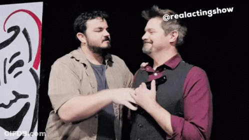 Two Men Are Standing Next To Each Other In Front Of A Sign That Says @Realactingshow . GIF