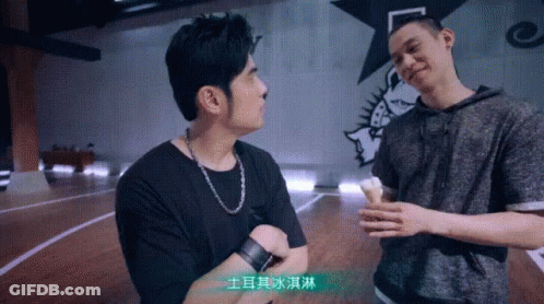 Two Men Are Standing Next To Each Other On A Basketball Court And One Of Them Is Holding An Ice Cream Cone . GIF