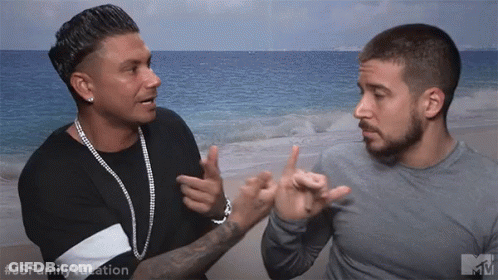 Two Men Are Standing Next To Each Other On A Beach And One Is Pointing At The Other 'S Face . GIF