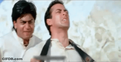 Two Men Are Standing Next To Each Other On A Beach . One Of The Men Is Holding A Gun . GIF