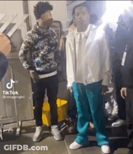 Two Men Are Standing Next To Each Other On A Sidewalk And Talking To Each Other . GIF