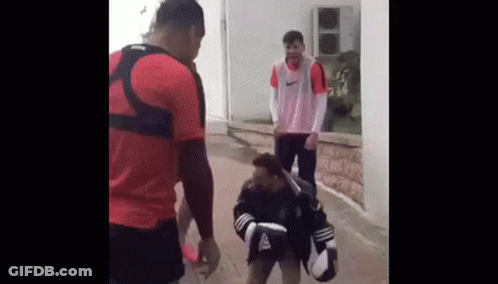 Two Men Are Standing Next To Each Other On A Sidewalk . GIF